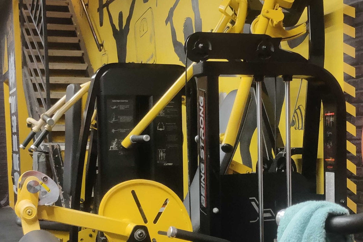 Being Strong Leg Extension and Curl Stations with Yellow Mural Wall